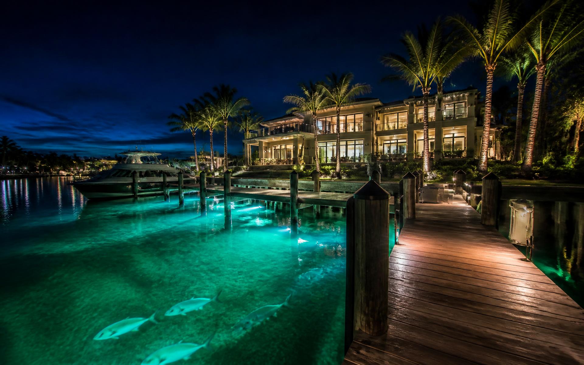 Luxury Southwest Florida waterfront dock at night glowing with cyan underwater lights